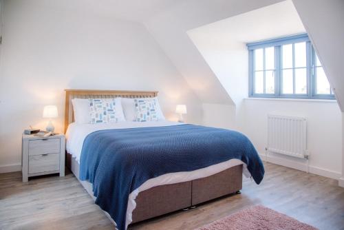 a white bedroom with a large bed and a window at 3 Oaks Court, Thorpeness in Thorpeness