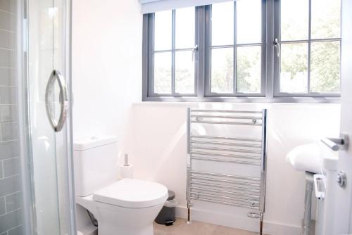 a white bathroom with a toilet and a window at 3 Oaks Court, Thorpeness in Thorpeness