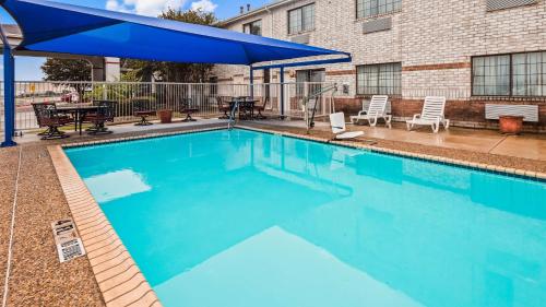 a large swimming pool with a blue umbrella over it at SureStay Plus by Best Western San Antonio Airport in San Antonio