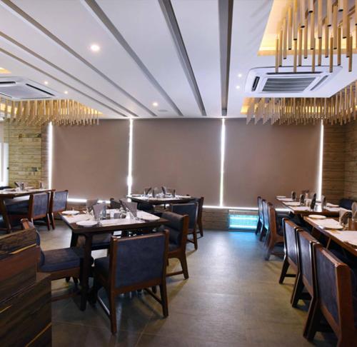 艾哈邁達巴德的住宿－優雅大飯店，用餐室配有桌椅和吊灯。