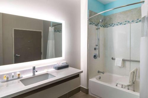 ein Badezimmer mit einem Waschbecken, einer Badewanne und einem Spiegel in der Unterkunft La Quinta by Wyndham Forsyth in Forsyth