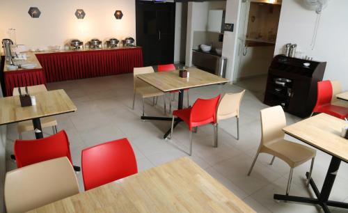 a restaurant with wooden tables and red chairs at Lavender Infopark Kochi in Kakkanad