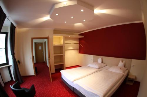 ein Schlafzimmer mit einem großen Bett mit einer roten Wand in der Unterkunft Hotel-Restaurant Zum Goldenen Löwen in Kelkheim