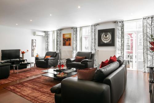 a living room with a leather couch and chairs at Lisbon Rentals Chiado in Lisbon