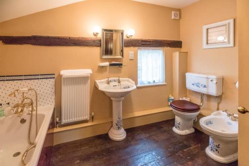 La salle de bains est pourvue d'un lavabo, de toilettes et d'une baignoire. dans l'établissement Cliftons Cottage, Clare, à Sudbury