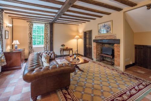 a living room with a leather couch and a fireplace at Cliftons Cottage, Clare in Sudbury