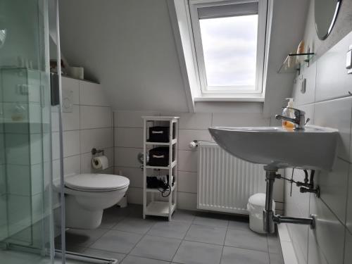 ein Badezimmer mit Waschbecken und Toilette und einem Fenster in der Unterkunft Wohnung Burgstaaken in Fehmarn
