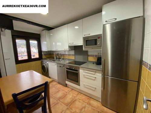 ベルメオにあるAurrekoetxea 36 Vacation Rental, 5Dのキッチン(ステンレス製の冷蔵庫、テーブル付)
