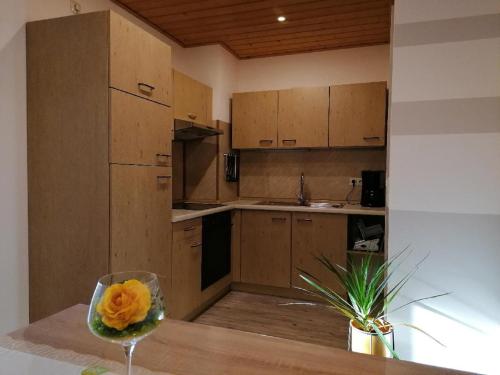 a kitchen with wooden cabinets and a flower in a glass at Ferienwohnung Michael Vogl in Bodenmais