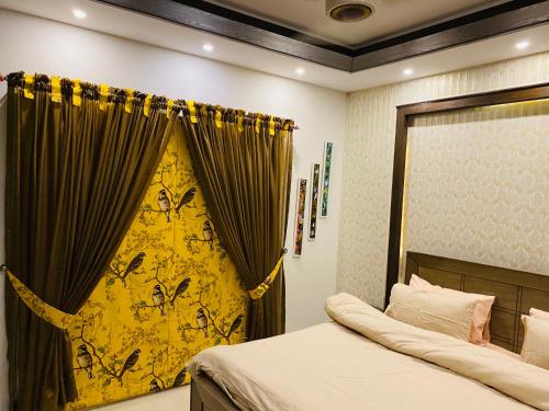- une chambre avec un lit et un rideau jaune dans l'établissement Independent Full House Dha 6 Lahore, à Lahore