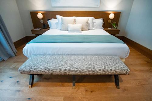 a large bed with a bench in a room at Soho Boutique Equitativa in Málaga