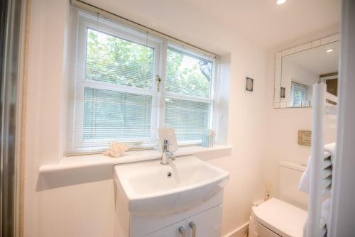 a white bathroom with a sink and a window at Little House, Aldringham in Leiston