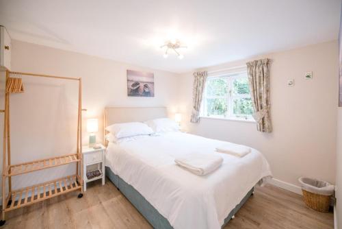 a bedroom with a large white bed with a mirror at Little House, Aldringham in Leiston