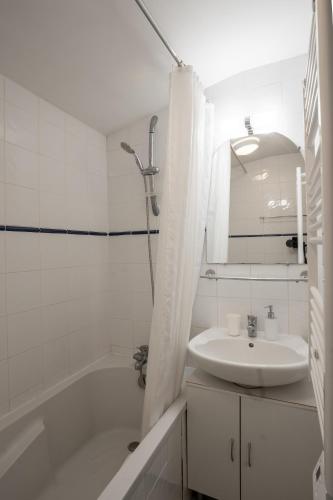 une salle de bain blanche avec une baignoire et un lavabo dans l'établissement La Closerie du Chêne Bleu, à Saint-Caprais-de-Blaye