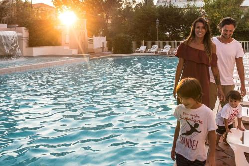 a family standing next to a swimming pool at Mansarda Cannes in Riccione