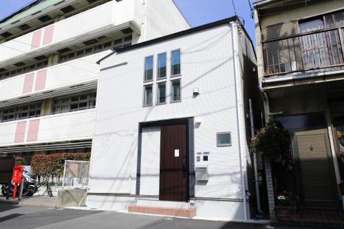 a white building with a brown door on a street at 羽田ハウスⅠ _ Haneda House Ⅰ in Tokyo