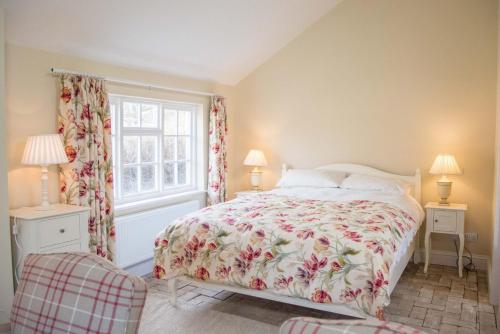 a bedroom with a bed with a floral bedspread and a window at Mill Cottage, Tunstall in Tunstall