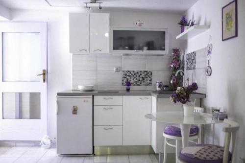 Il comprend une cuisine blanche avec une table et une télévision. dans l'établissement Holiday Home Lavanda, à Raslina