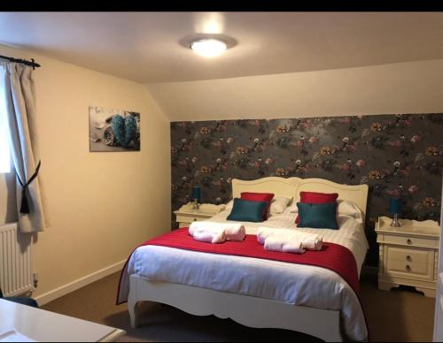 a bedroom with a large bed with red and green pillows at The Jug & Glass Inn in Hartington
