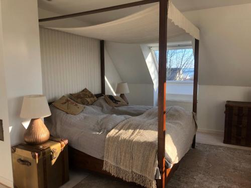 a bedroom with a canopy bed and a window at Det gamle badehotel i Grasten in Svendborg