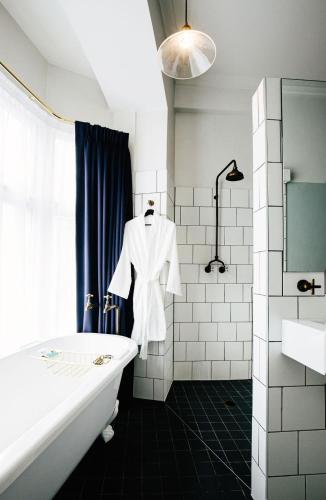 a bathroom with a white robe hanging on the wall at Hotel Harry, an Ascend Collection Hotel in Sydney