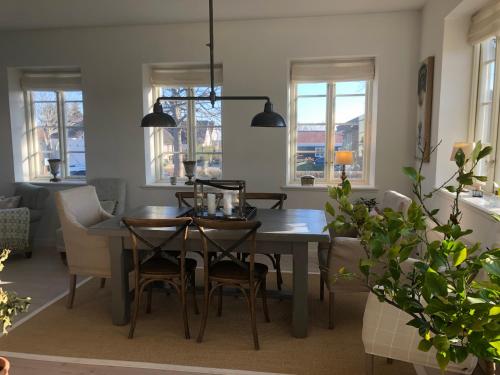 a dining room with a table and chairs and windows at Det gamle badehotel i Grasten in Svendborg