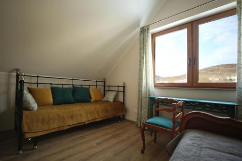 a bedroom with a bed and a window and a chair at Domek Chmielnik in Pieszyce