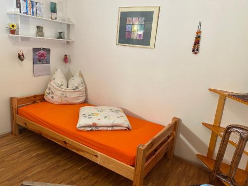 a bed in a room with an orange mattress at Haus am Waldpark in Scheidegg