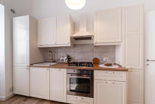 una cucina con mobili bianchi e un forno a piano cottura di Casa Donna Gina - Puglia Mia Apartments a Monopoli
