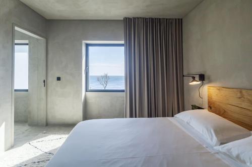 a bedroom with a large bed and a large window at CASA DA ILHA - Slow Living Residence & Suites in Ponta Delgada