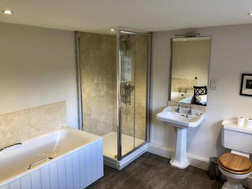 a bathroom with a tub, toilet, sink and shower at The Dorset Arms Cottage & Pub Rooms in Groombridge