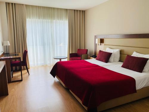 a hotel room with a large bed with a red blanket at Placido Hotel Douro - Tabuaco in Tabuaço