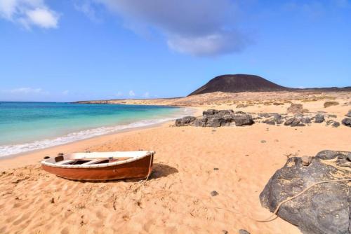 a wooden boat sitting on a beach next to the ocean at Villa Tamia & Atlántico Marina Rubicón in Playa Blanca