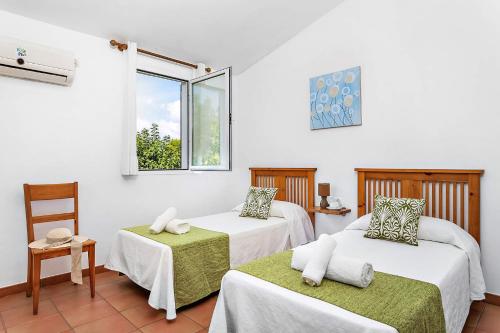 una habitación con dos camas y una ventana en Villas Nura, en Son Carrio