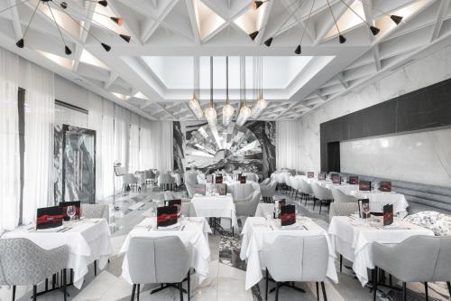 a restaurant with white tables and chairs and a chandelier at Hotel Riu Palace Tikida Taghazout - All Inclusive in Taghazout
