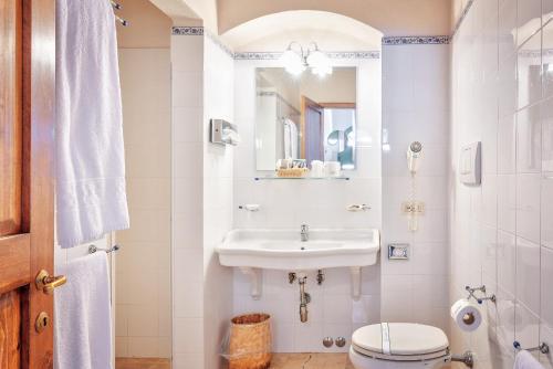 a bathroom with a sink and a toilet and a mirror at Hotel Borgo Casabianca in Serre di Rapolano