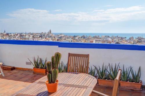a balcony with a wooden chair and cacti at Linda Vista Oasis Penthouse by Hello Homes Sitges in Sitges