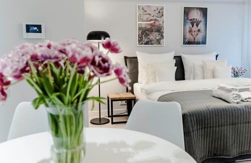 a vase of flowers on a table next to a bed at MENNICA RESIDENCE PATRONUS Apartments in Warsaw