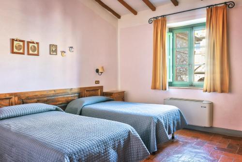 a bedroom with two beds and a window at Hotel Borgo Casabianca in Serre di Rapolano