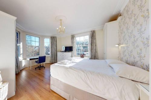 a bedroom with a large white bed and windows at Superb 2 bedroom flat w garden - 1 min to Queen's Park in London