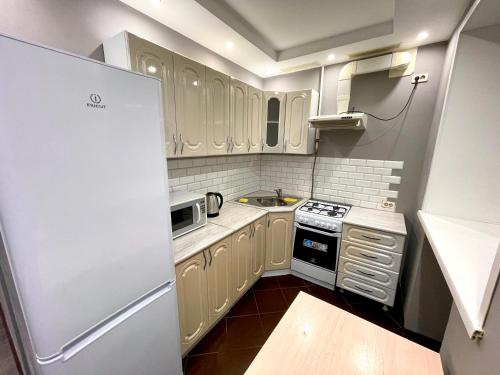 a small kitchen with white cabinets and a refrigerator at Apartment on Krasnoarmeyskaya in Kemerovo
