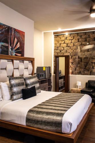 a bedroom with a large bed and a stone wall at Hoteles ANTIGUA - SANTA LUCIA MTY in Monterrey