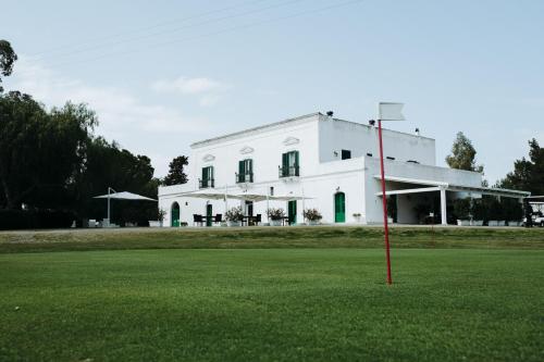 a white building with a red pole in the middle of a field at Golf Club Metaponto in Metaponto