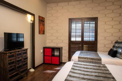 a bedroom with two beds and a flat screen tv at Hoteles ANTIGUA - SANTA LUCIA MTY in Monterrey