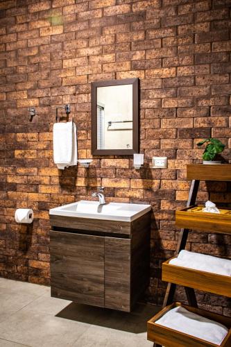 a bathroom with a sink and a mirror on a brick wall at Hoteles ANTIGUA - SANTA LUCIA MTY in Monterrey