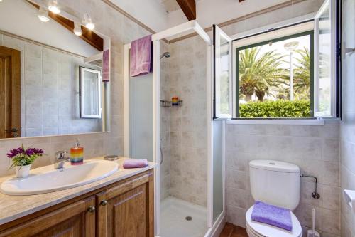 a bathroom with a sink and a toilet and a window at Villa Menorca Juanita by Mauter Villas in Cala en Blanes