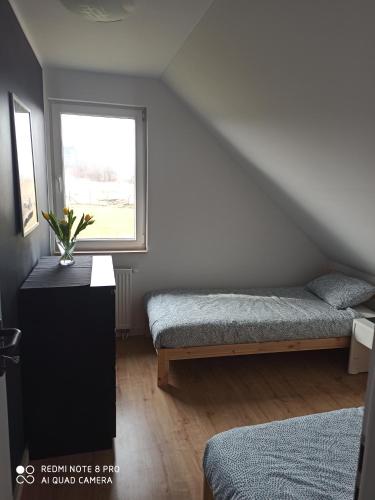 a attic bedroom with two beds and a window at Domek Całoroczny Pod Dworem in Wola Kalinowska