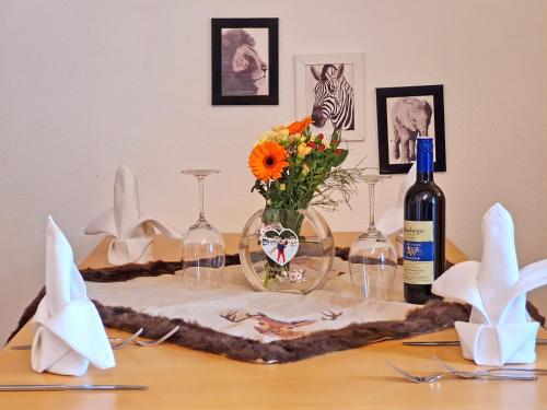 a table with a vase of flowers and a bottle of wine at Appartementhotel Zugspitzhof in Ehrwald