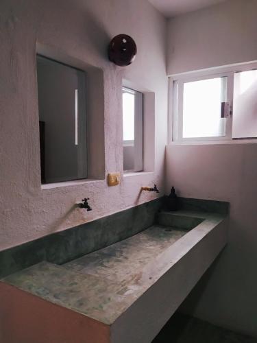Hotel Jardin Mahahual في ماهاهوال: حمام مع حوض كبير ومرآة