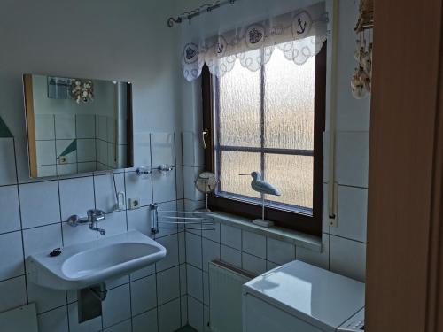 a white bathroom with a sink and a window at "Kleine Hedwig" in Putbus